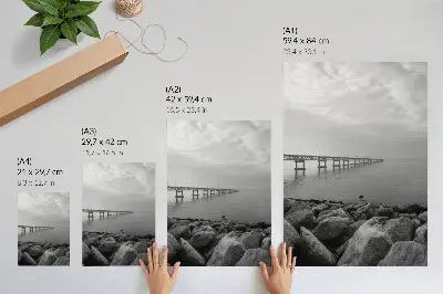 Nowoczesna grafika na płótnie spokojny pejzaż z mostem na kamienistej plaży przy szarym niebie